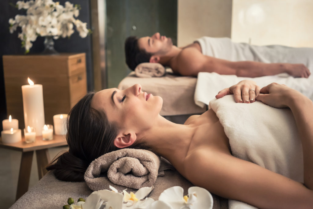 Young Man And Woman Lying Down On Massage Beds